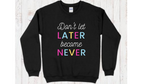 Black crewneck sweatshirt with "don't let later become never" quote with pink, blue, and yellow lettering