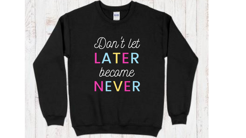 Black crewneck sweatshirt with "don't let later become never" quote with pink, blue, and yellow lettering