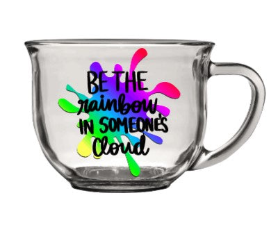 Clear glass mug with rainbow splatter and "be the rainbow in someone's cloud" text